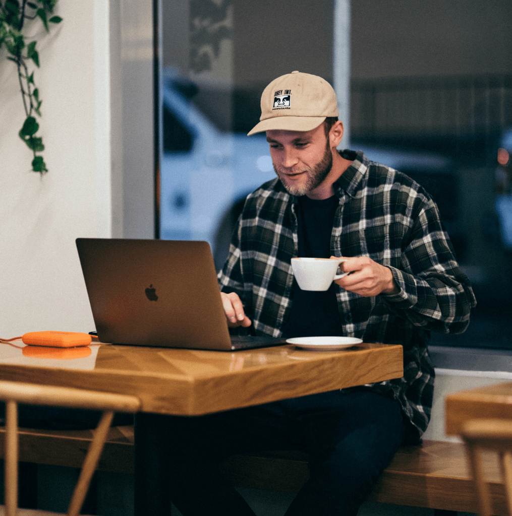Man sat at desk with coffee and laptop learning how to become an app creator